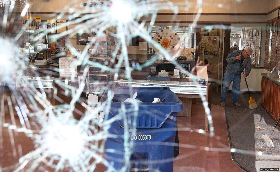 A worker cleans up glass at a business that was damaged during a demonstration on November 25, 2014