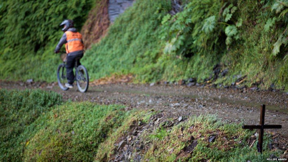 A cyclist cycles past a cross on the Yungas road on 6 September 2014