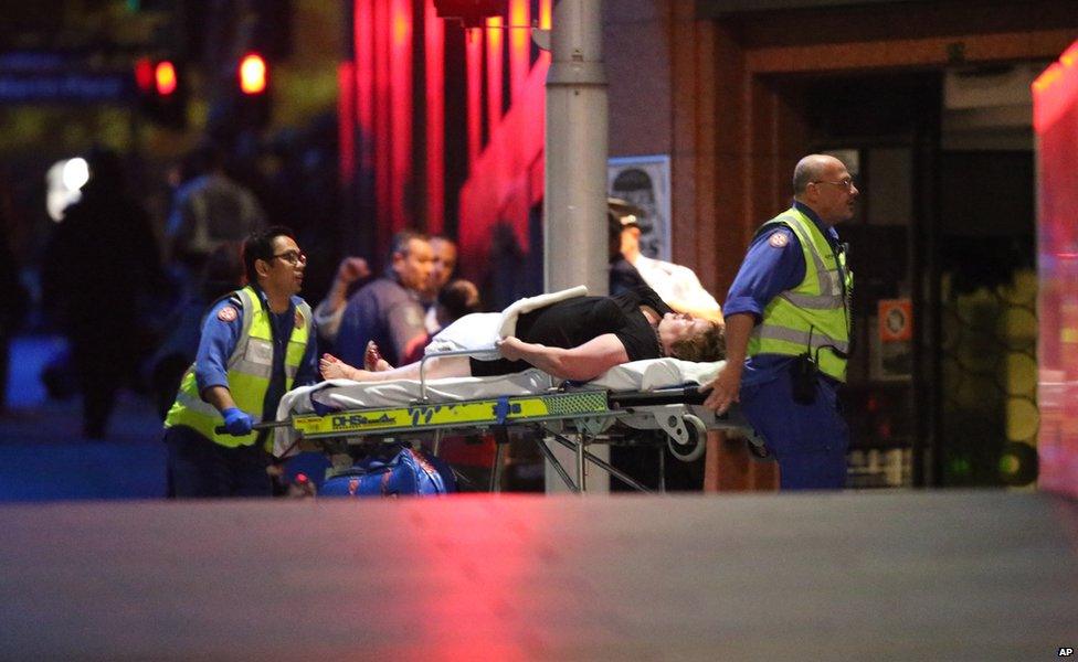 A injured hostage is wheeled to an ambulance after shots were fired during a cafe siege at Martin Place in the central business district of Sydney, Australia, Tuesday, Dec. 16, 2014