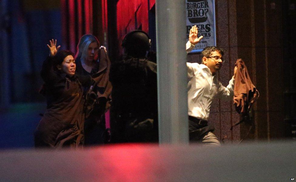 Hostages run to safety during a cafe siege in the central business district of Sydney , Australia, Tuesday, Dec. 16, 2014