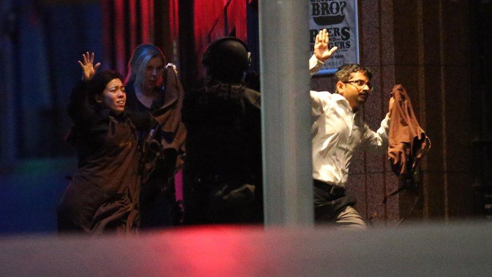 Hostages run to safety during a cafe siege in the central business district of Sydney , Australia, Tuesday, Dec. 16, 2014