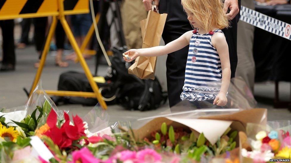 A young girl holds aloft a chocolate over memorial flowers on December 16, 2014 in Sydney.