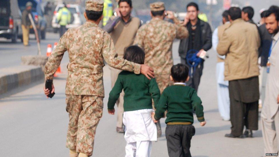 A soldier escorts schoolchildren away from a school attacked by gunmen in Peshawar