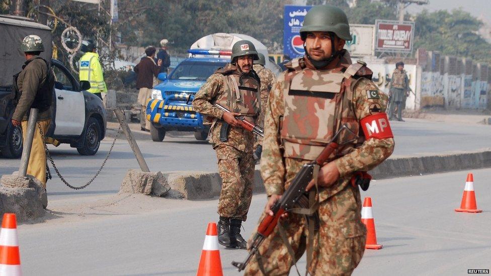 Pakistani army troops guard a road near an armed incident in Peshawar