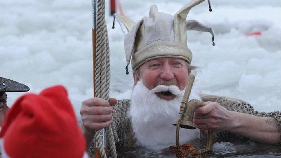 A swimmer in a Father Christmas costume at a festive swim in Cornwall