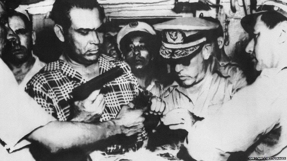 Batista inspects weapons seized in an attempted revolt, 1953