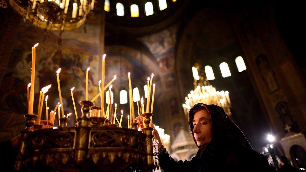 An elderly woman lights a candle during the Christmas Holy mass at the St Alexander Nevski Cathedral in Sofia, Bulgaria on Christmas Day, 25 December 2014