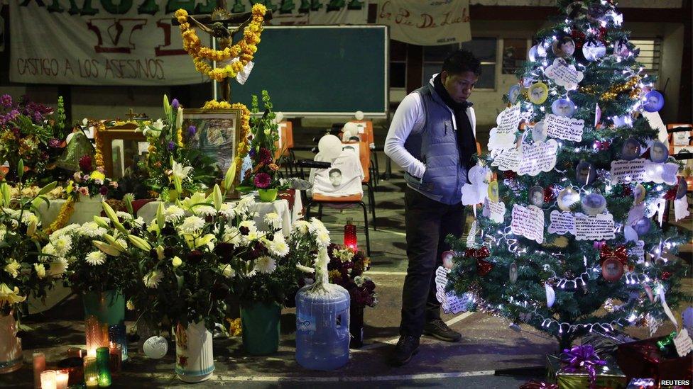 A man looks at a Christmas tree, with pictures of the 43 missing trainee teachers, next to an altar in the Ayotzinapa Teacher Training Raul Isidro Burgos College in Ayotzinapa, on the outskirts of Chilpancingo, Guerrero, December 24, 2014. Mexican authorities on December 7 said that mounting evidence and initial DNA tests confirmed that 43 trainee teachers who were abducted in Iguala by corrupt police on September 26 were incinerated at a garbage dump by drug gang members.