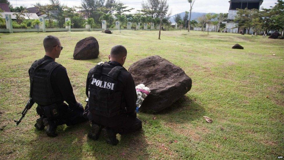 Policemen pray for their dead friends and relatives at a mass grave in Banda Aceh, Indonesia. Photo: 26 December 2014