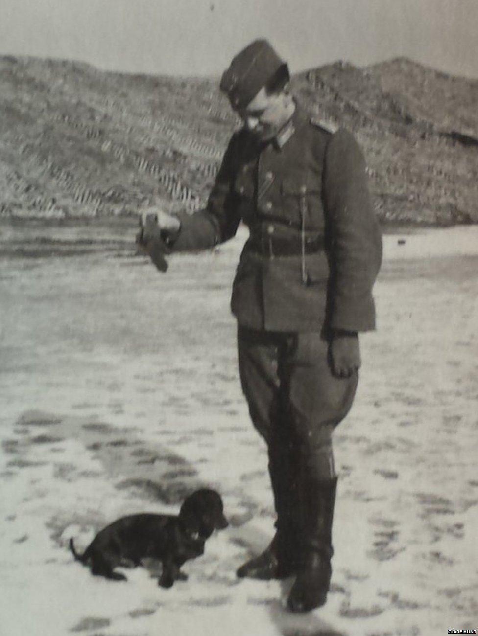 Ein deutscher Offizier spielt mit einem Dackel am Strand