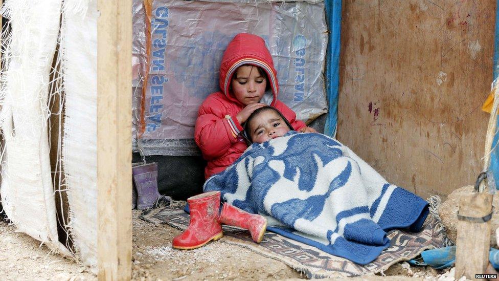 A Syrian refugee girl sits with her brother at a makeshift settlement in Bar Elias in the Bekaa valley, 5 January 2015