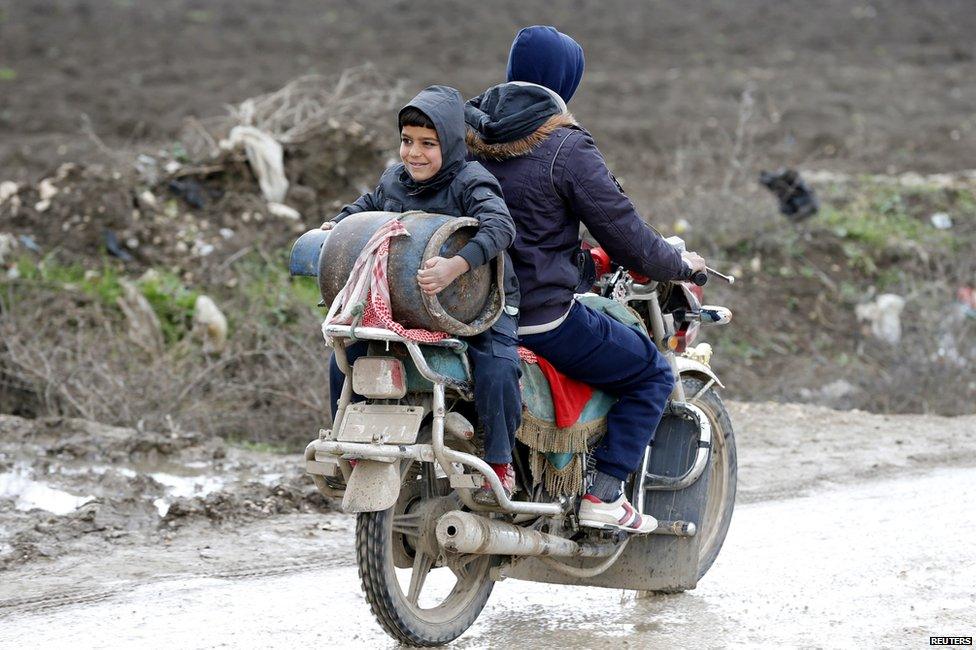 A Syrian refugee boy carries a gas canister on a motorcycle near a makeshift settlement in Bar Elias in the Bekaa valley, 5 January 2015