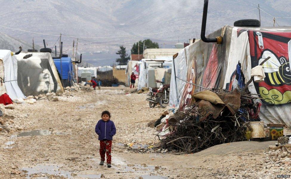 A Syrian refugee girl walks outside tents at a makeshift settlement in Bar Elias in the Bekaa valley, 5 January 2015