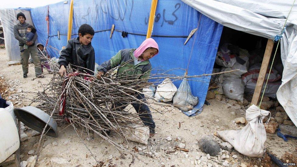 Syrian refugee boys carry wood to be used for heating at a makeshift settlement in Bar Elias in the Bekaa valley, 5 January 2015