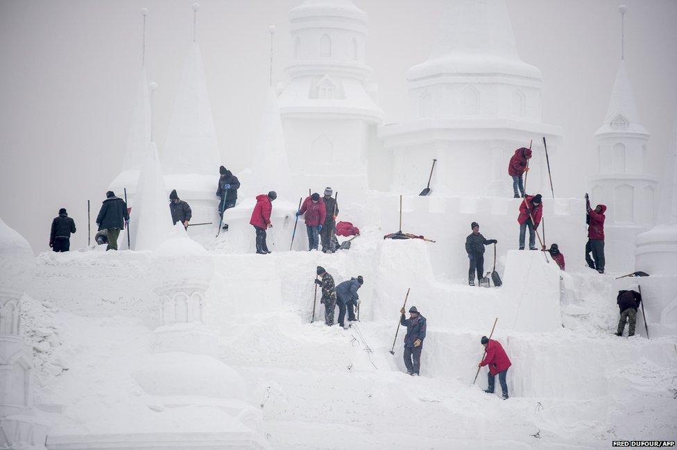 Ice sculptors carve a snow sculpture