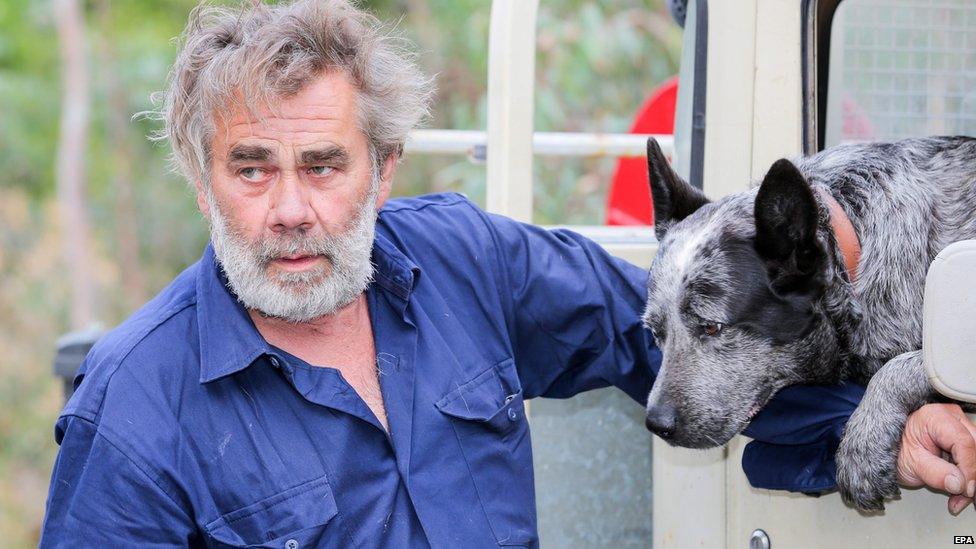 Kersbrook resident David Miller and his dog Zeus wait for road blocks to be lifted around his property in Kersbrook, in the Adelaide Hills