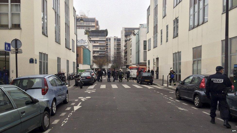 Police officers and fire fighters gather in front of the offices of the French satirical newspaper Charlie Hebdo in Paris on 7 January 2015