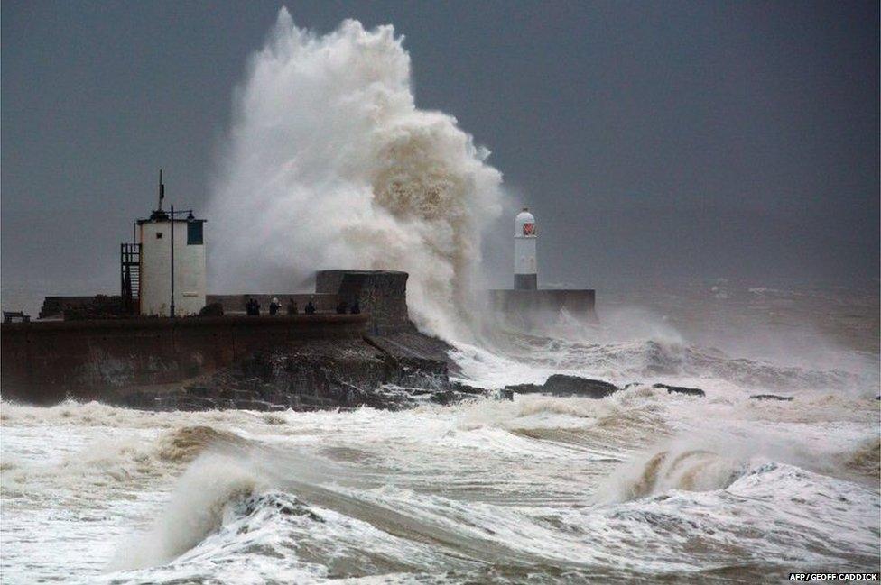 People watch and photograph as large waves batter the harbour wall and lighthouse at Porthcawl in south Wales on 10 January