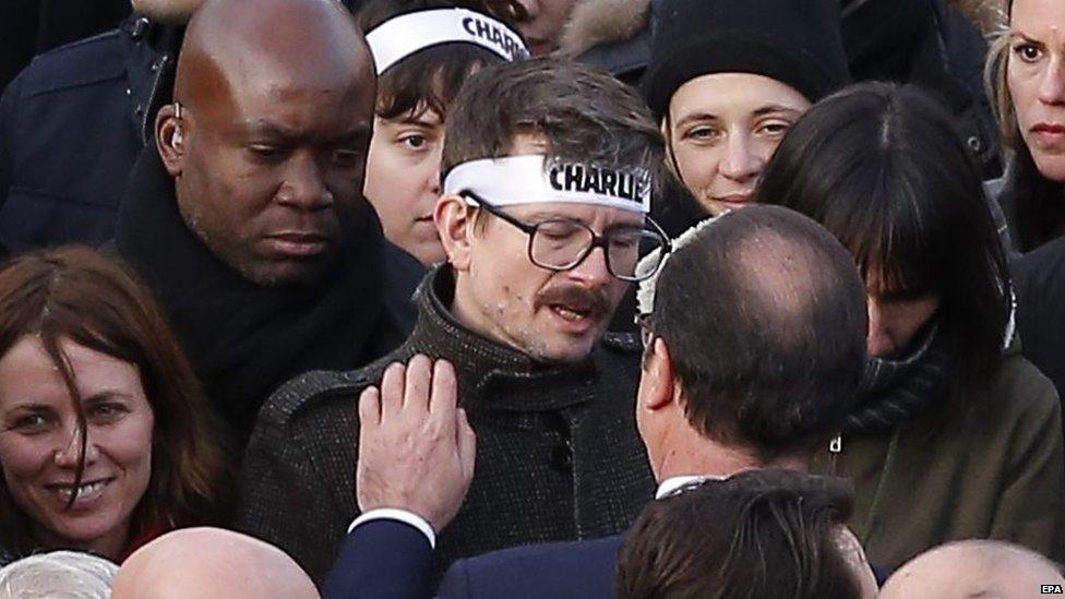 French President Francois Hollande speaks to French caricaturist Luz during the course of the march