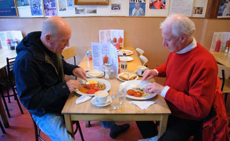 Two gentlemen eat breakfast at Alpino cafe, Islington, London