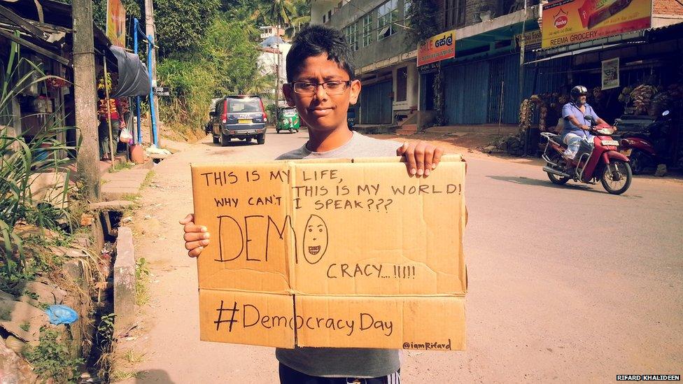 Boy holding a poster made from the side of a cardboard box