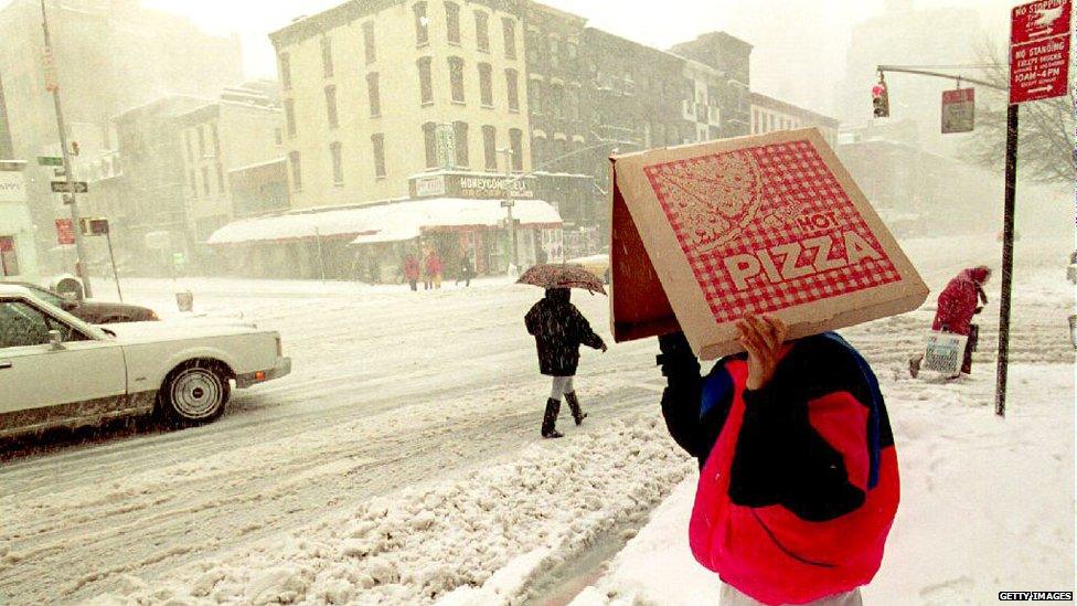 izza delivery man shields himself from the blizzard conditions pounding New York City and most of the east coast of the U.S. as he waits to cross second Avenue 13 March 1993P