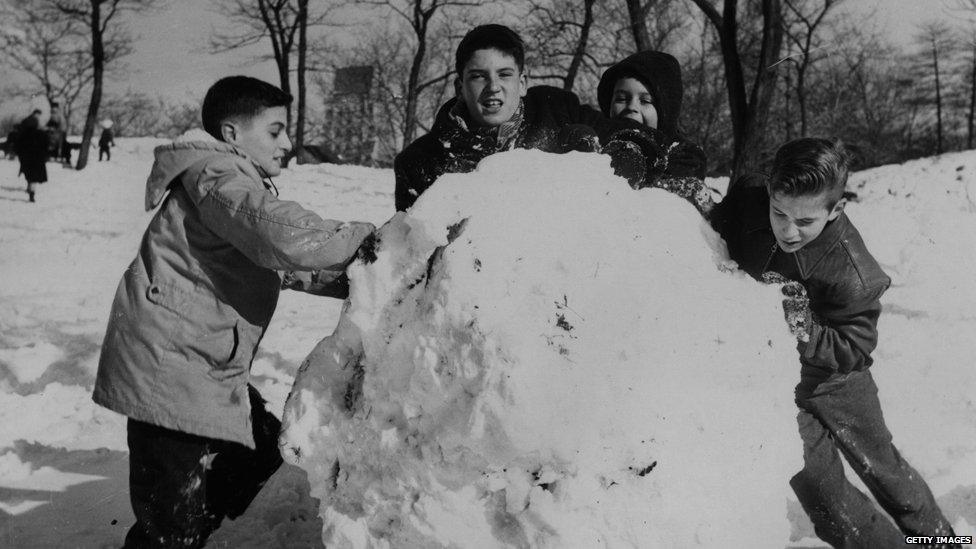 A group of boys rolling what may be New York's biggest snowball in Central Park circa 1960