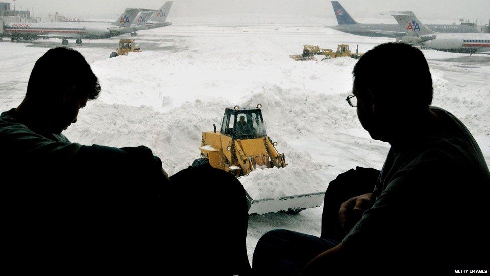 Two passengers stare out the window at the snow-clogged tarmac as they await their delayed flight February 18, 2003 at LaGuardia Airport in the Queens borough of New York City