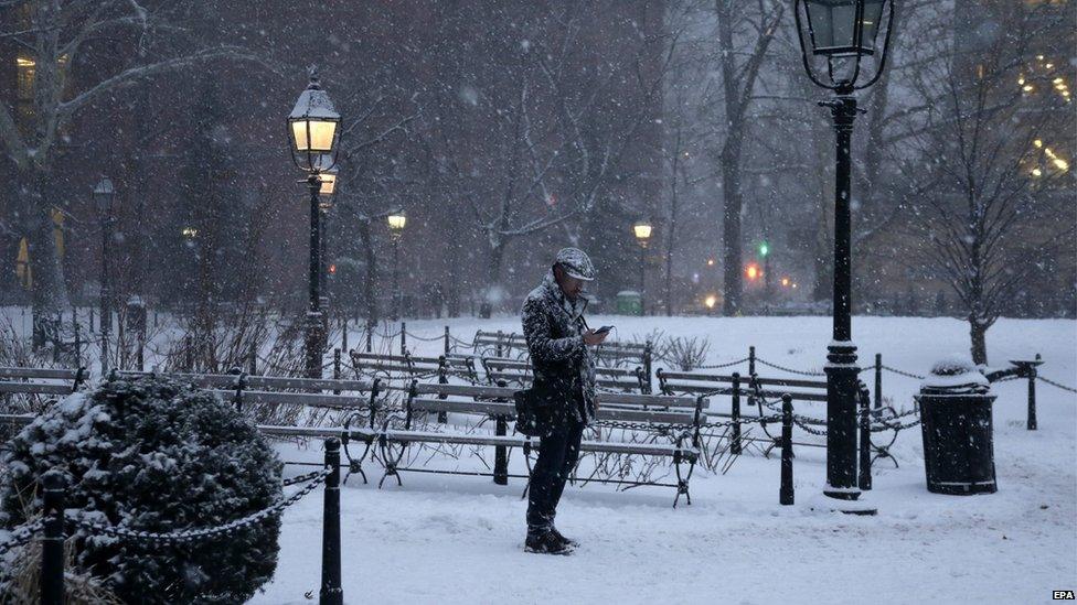 a man walking through a snowy park in New York