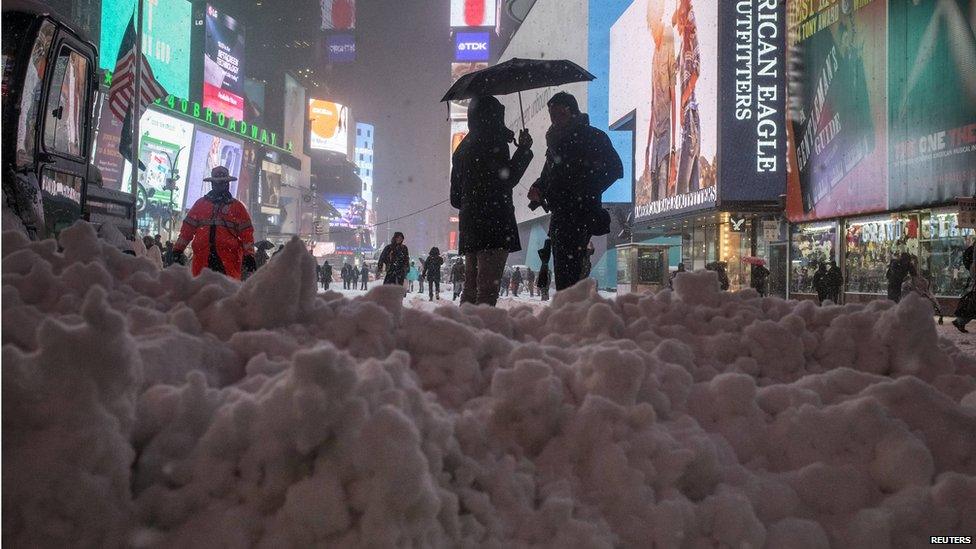 two people talking next to a large pile of snow.