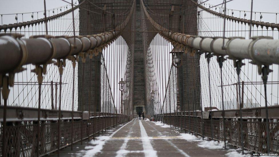 A couple walk on the Brooklyn Bridge in New York after a snowstorm