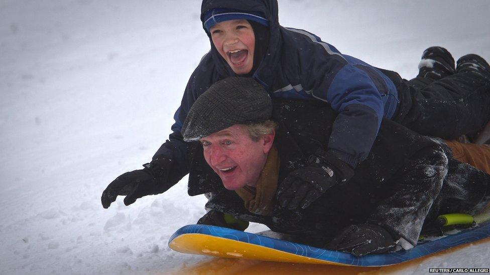 A man and boy ride a sled down Cedar Hill in Central Park