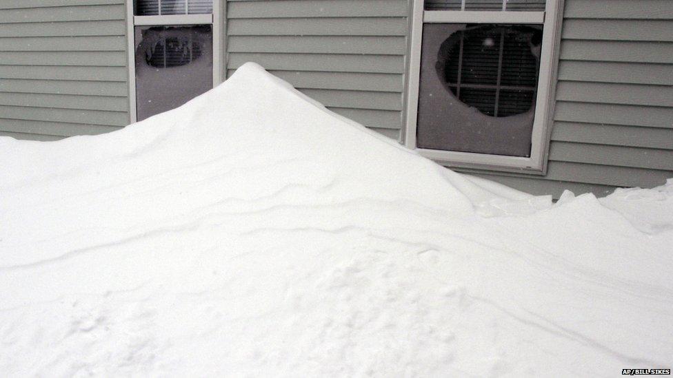 Drifted snow is piled along the wall of a house after a winter storm, Tuesday, Jan. 27, 2015, in Marlborough, Mass