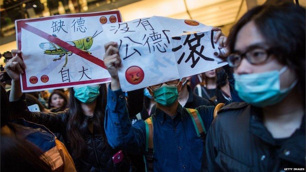 Protesters hold signs outside a shopping centre in Hong Kong (16 Feb 2015)