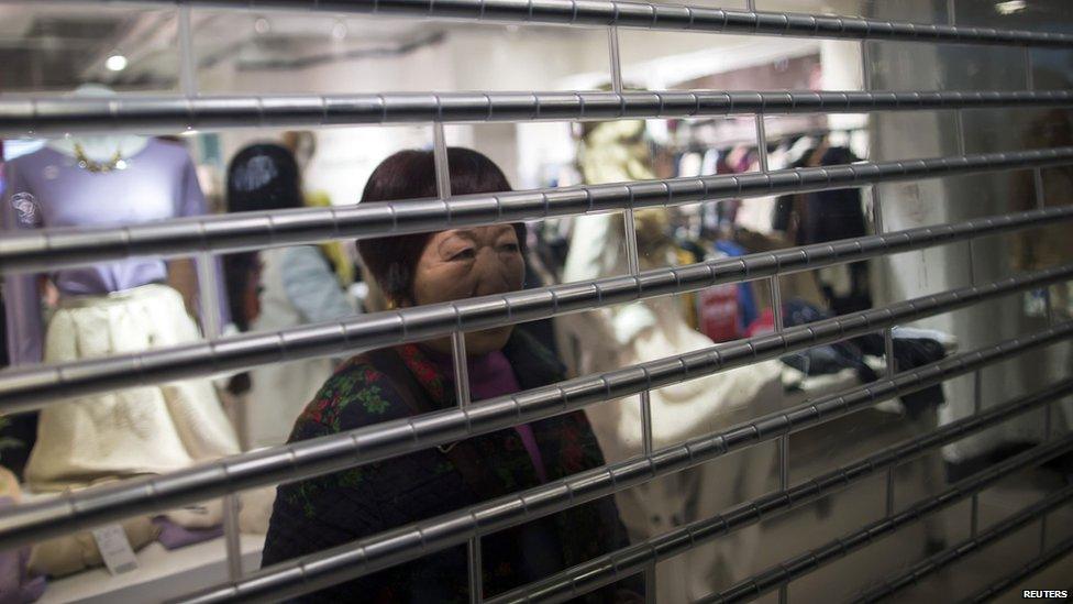 A Chinese woman behind a shop shutter in Hong Kong (15 Feb 2015)