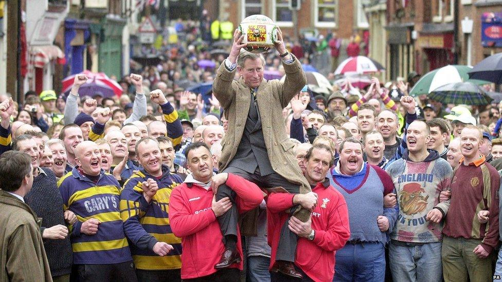 Prince Charles being lifted up holding the ceremonial ball before starting the ancient Royal Shrovetide Football game, in Ashbourne, Derbyshire. Holding the Prince shoulder-high were Dougie Souter and Mark Harrison (right of Prince with dark hair).