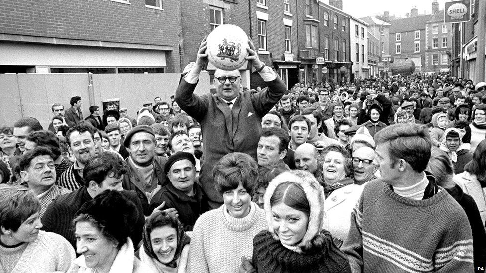 The Earl of Yarborough performs his duties as the honorary 'turner up of the ball'. He is carried on the shoulders of competitors to the start in Shaw Croft field.