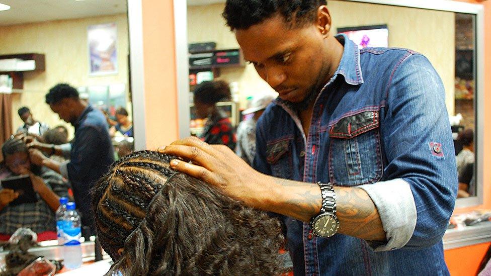 A hairdresser sewing on a weave at Bruno's Place hair salon in Ikeja Mall in Lagos, Nigeria