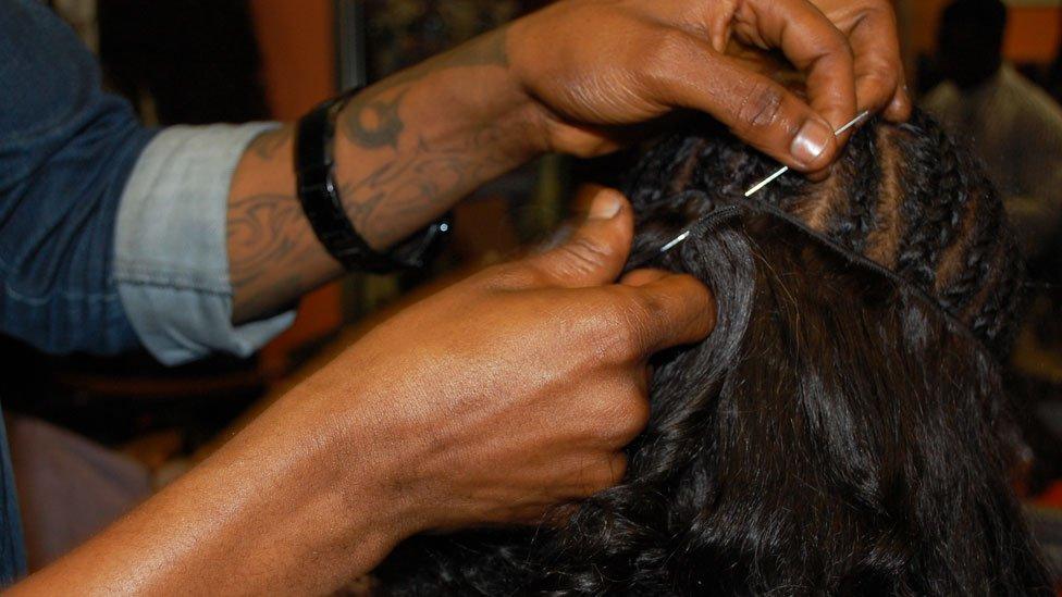 A hairdresser sewing on a weave at Bruno's Place hair salon in Ikeja Mall in Lagos, Nigeria