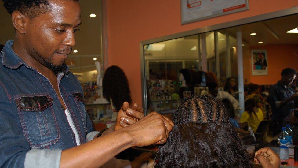 A hairdresser sewing on a weave at Bruno's Place hair salon in Ikeja Mall in Lagos, Nigeria