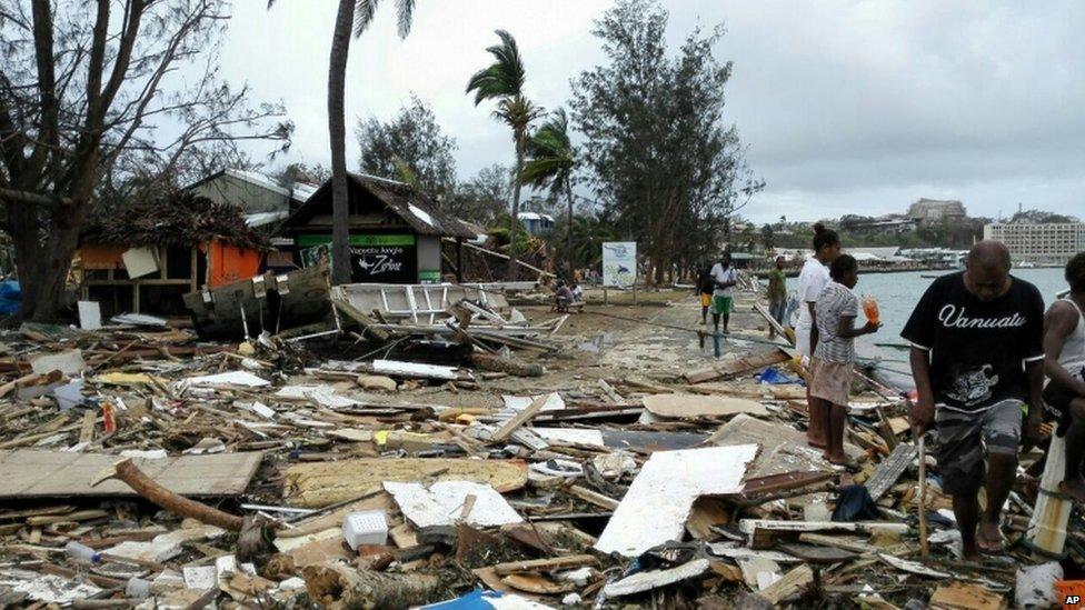 In this photo provided by China's Xinhua News Agency, locals walk past debris in Port Vila, Vanuatu, after Cyclone Pam ripped through the tiny South Pacific archipelago, Sunday, 15 March 2015