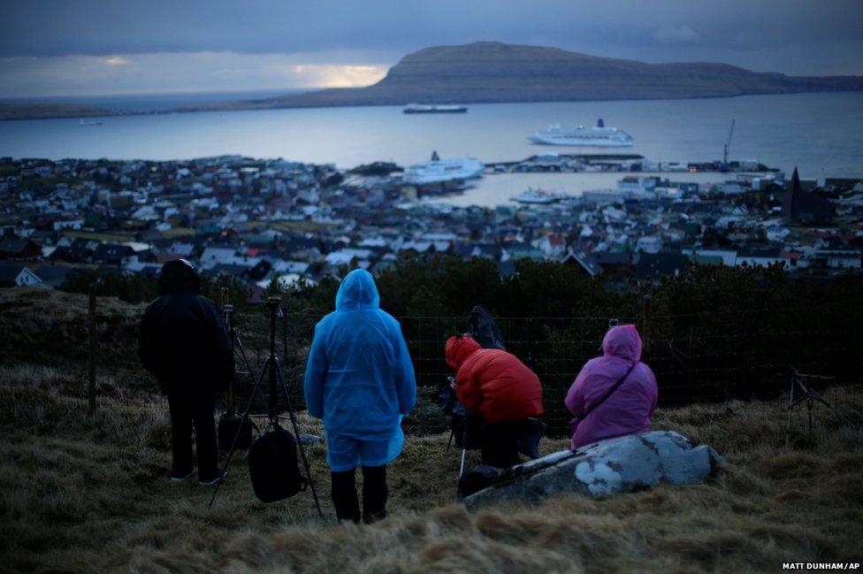 People wait for the start of a total solar eclipse in Torshavn, the capital city of the Faroe Islands