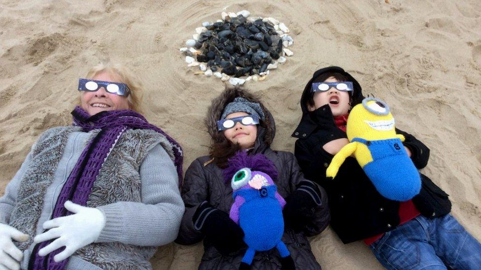 Children and woman watching an eclipse