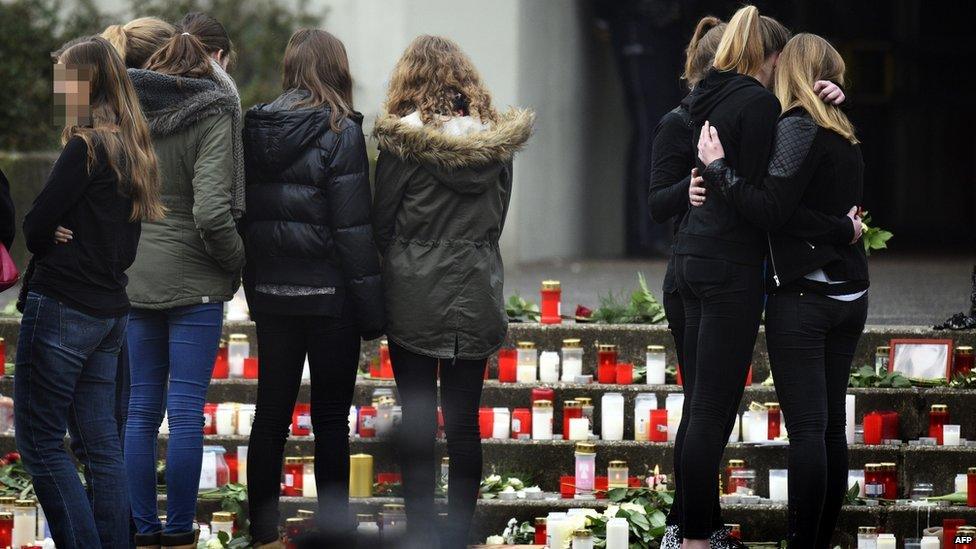 Students gather at a memorial of flowers and candles in front of the Joseph-Koenig-Gymnasium secondary school