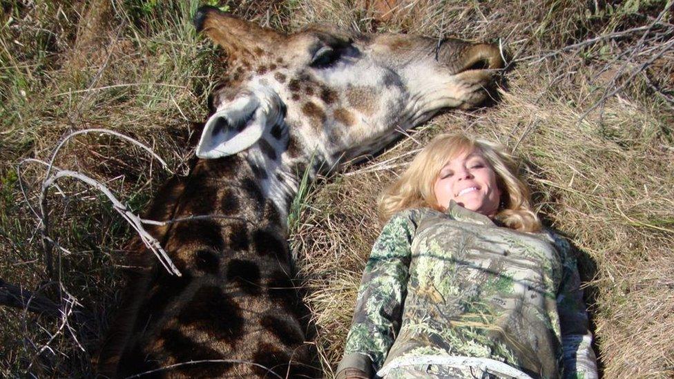 Rebecca Francis smiles as she lies next to dead giraffe