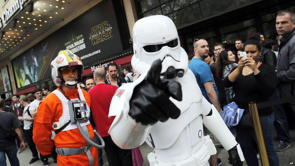 A man dressed as a Stormtrooper walks past people as they queue to attend the steaming of Star Wars Celebration