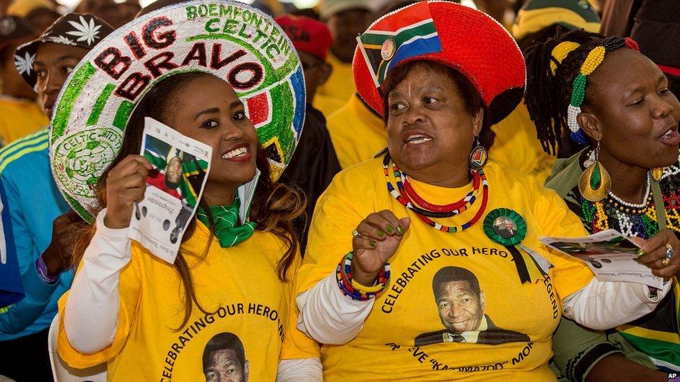 Mourners attend a memorial service for the late South African footballer, Steve "Kalamazoo" Mokone, portrait on tee shirts, at the FNB Soccer Stadium in Soweto, Johannesburg, Saturday, 11 April 2015