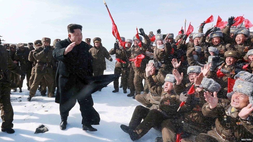 Kim Jong-Un, walking in front of troops, on top of a mountain