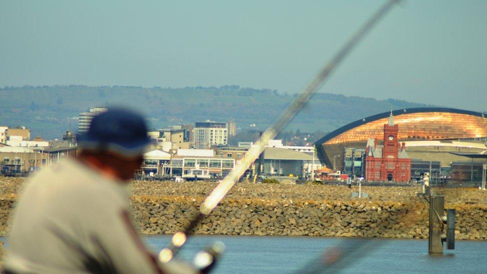 Cardiff Bay as a fisherman looks on.