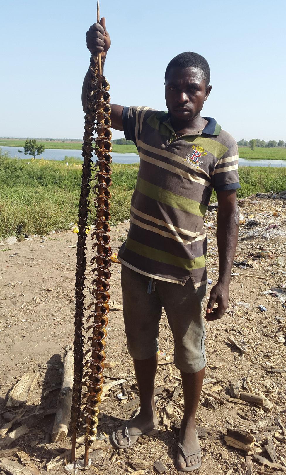 Philip Paul holding a skewer of frogs